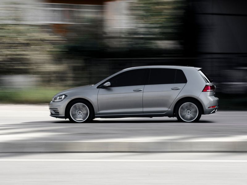 A silver hatchback car photographed in motion on a road